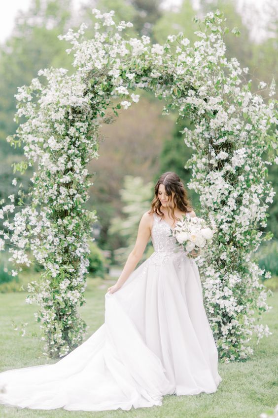 a spring wedding arch covered with white blooming branches is a cool idea for a lovely and relaxed spring wedding