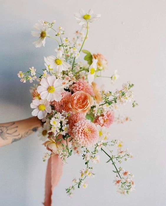 a spring wedding bouquet of blush and peachy mums and ranunculus, white cosmos and chamomiles plus blooming branches
