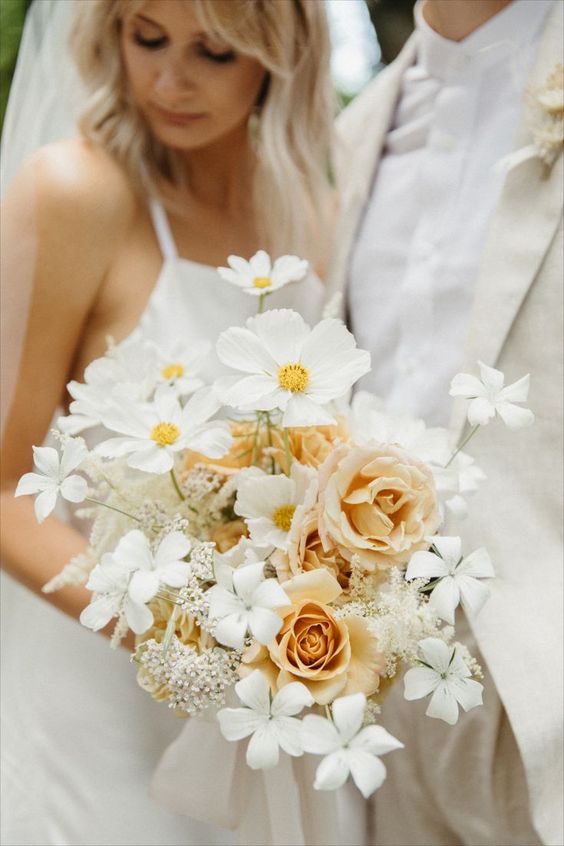 a stylish modern wedding bouquet of white cosmos, peachy roses and white blooms and fillers is a cool and chic diea