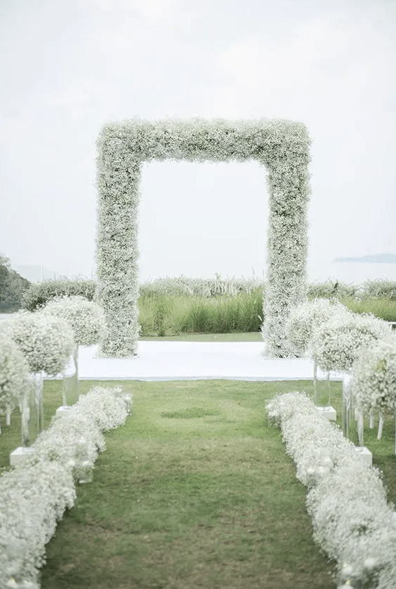 a stylish modern wedding ceremony space with a baby's breath arch, tall and low matching arrangements