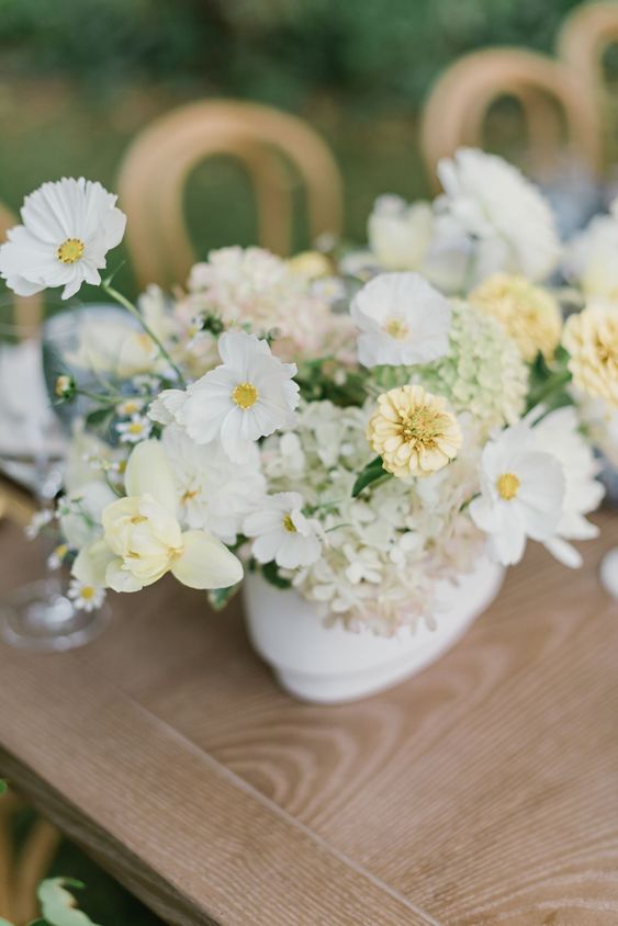 a summer wedding centerpiece of white cosmos and light green and yellow fillers is a cool decoration to rock
