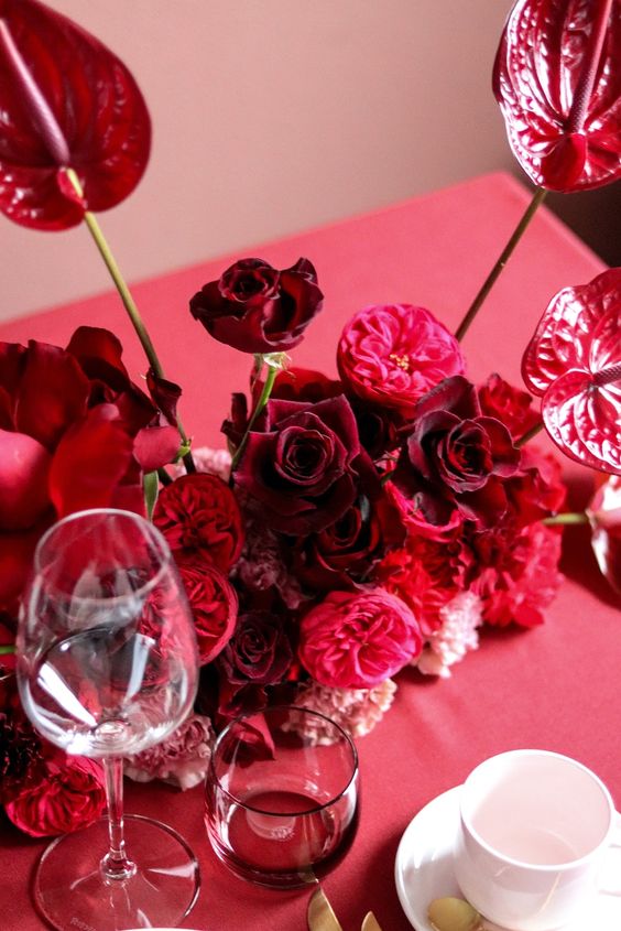 A sumptuous colored wedding centerpiece of burgundy roses, pink and red peony roses and anthuriums will fit a fall wedding
