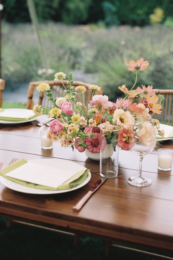 a sunset-colored centerpiece of pink and peachy cosmos, yellow fillers and pink roses is a cool idea for a late summer wedding