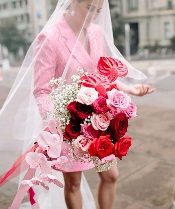 a super colorful wedding bouquet of red, burgundy and pink roses, blush orchids and pink anthuriums plus baby’s breath