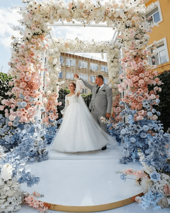 a super lush pastel wedding arch covered with white, pink and serenity blue flowers creating an ombre effect