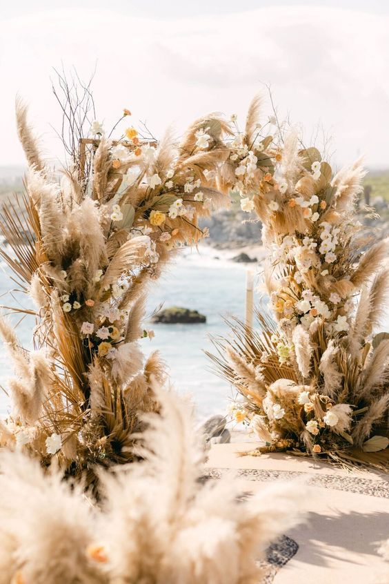 a super lush wedding arch with fronds, pampas grass, leaves, white and yellow roses is amazing for a summer wedding
