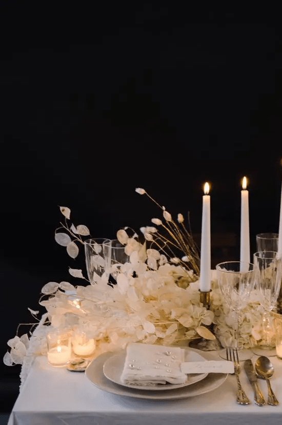 a super lush wedding centerpiece of lunaria and bunny tails and small and tall candles is a lovely and chic idea for a neutral wedding