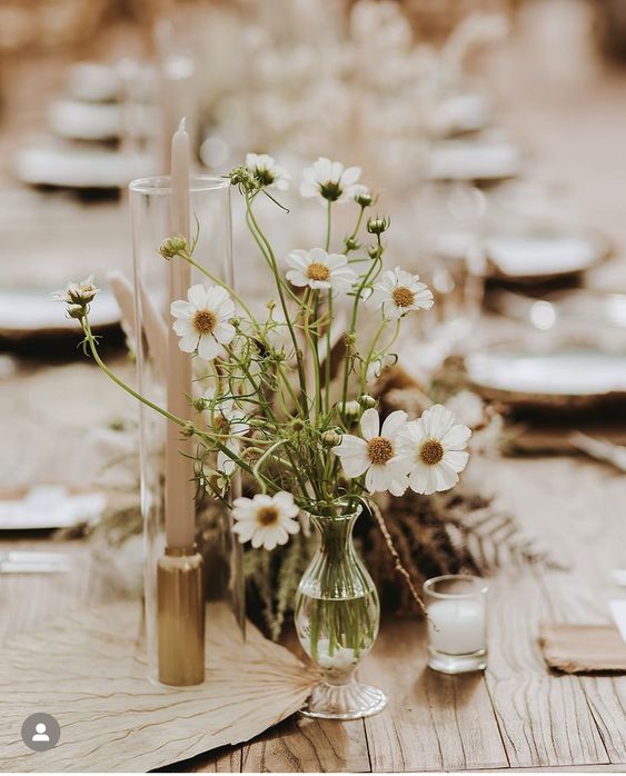 a super simple wedding centerpiece of a clear glass vase with cosmos is a cool idea for spring and summer