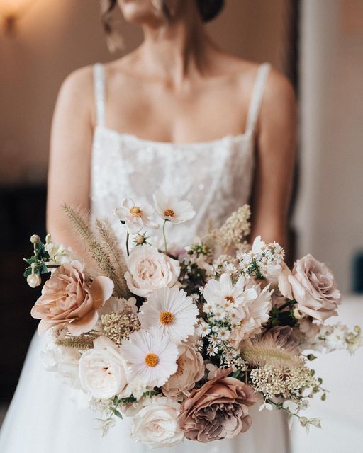 a textural wedding bouquet of white cosmos, dusty pink roses, chamomiles, grasses and some fillers