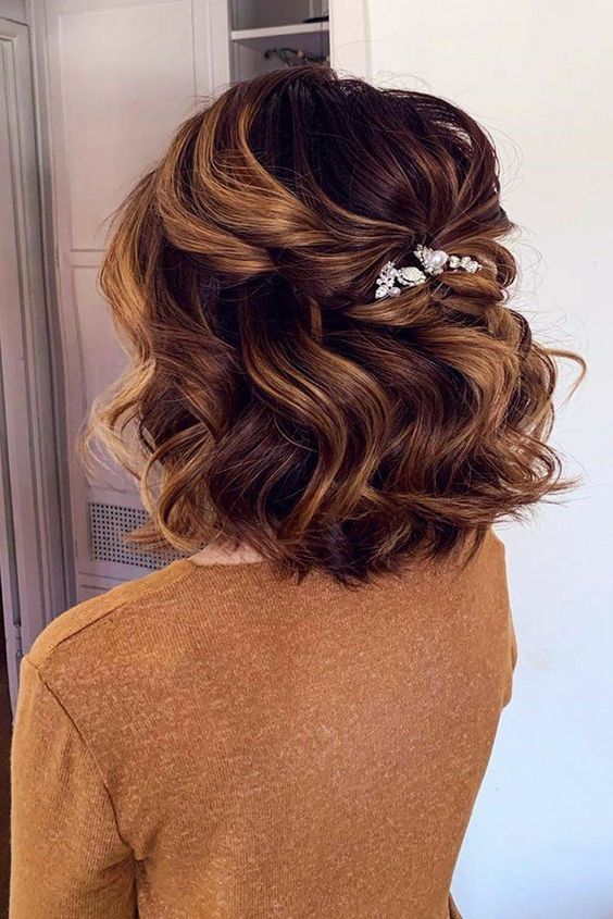 a volumetric and wavy half updo with a bump on top, waves down and an embellished hair piece is great for a wedding