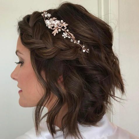 a wavy and volumetric half updo with a large loose braid on one side, an embellished hair vine and a bump on top