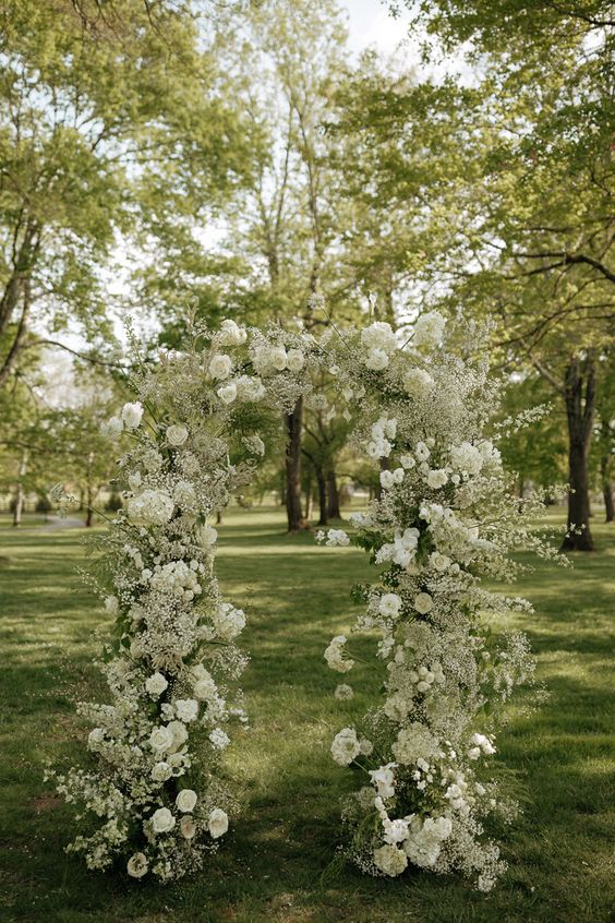 a white wedding arch covered with baby’s breath, roses and some white fillers is a chic idea for a spring or summer wedding