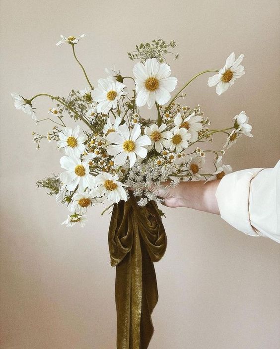 a white wedding bouquet of cosmos and chamomiles is a stylish solution for a spring or summer wedding