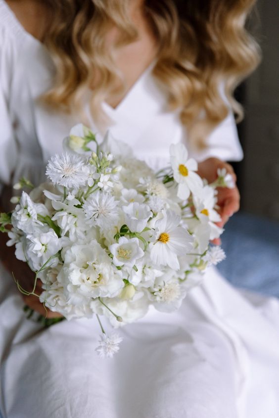 a white wedding bouquet of cosmos, sweet peas and other blooms is a cool idea for a modern neutral wedding