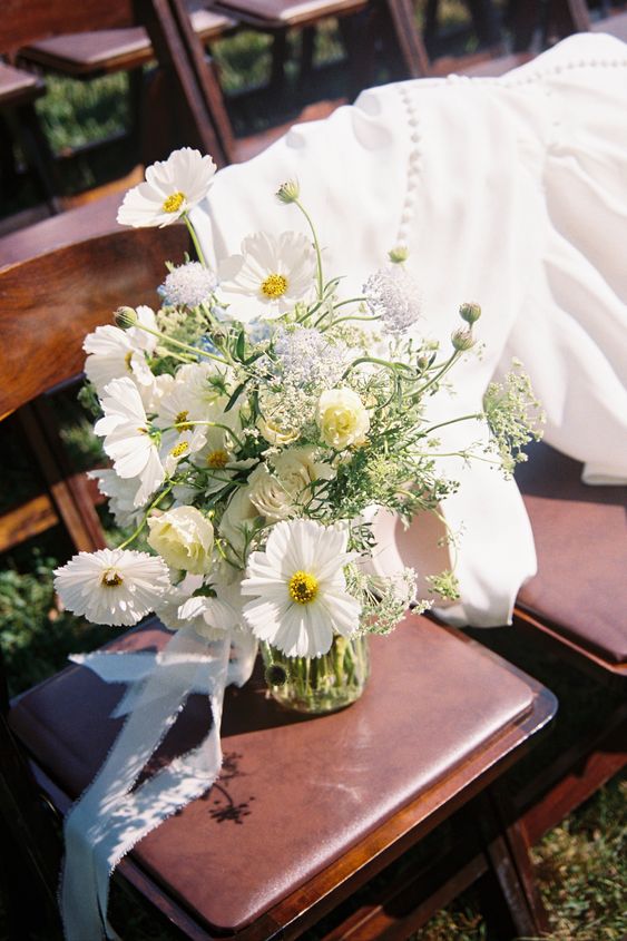 a white wedding centerpiece of cosmos and roses and some fillers is a cool idea for spring and summer