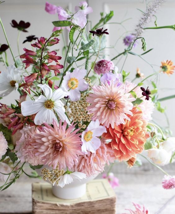 A wild looking wedding centerpiece of white cosmos, pink and orange dahlias, lilac and burgundy fillers