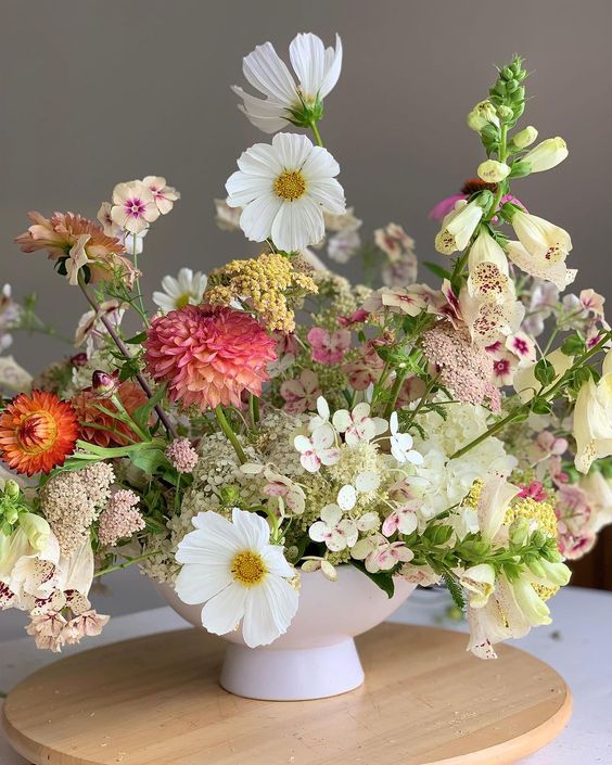 a wild summer wedding centerpiece of white cosmos, burgundy dahlias, greenery and some fillers is wow