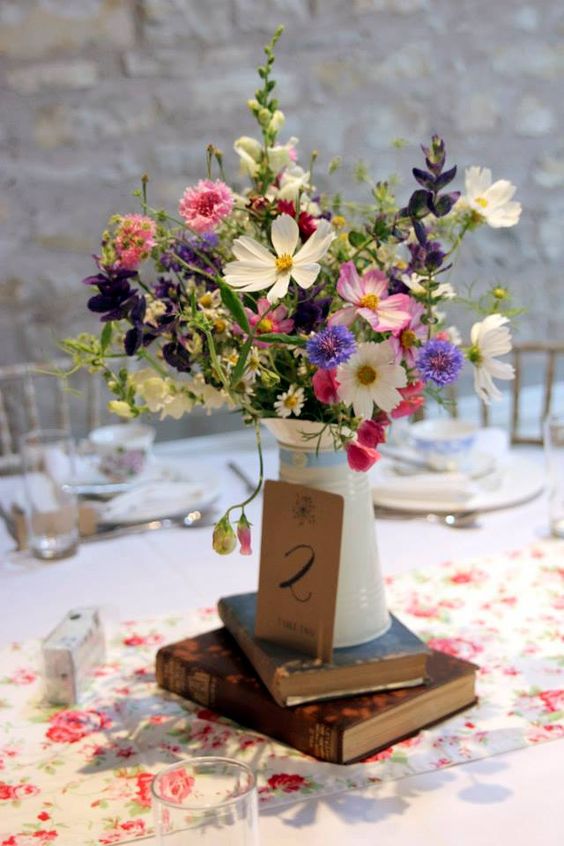 a wildflower wedding centerpiece of pink and white cosmos, purple and pink wildflowers and greenery for a relaxed summer wedding