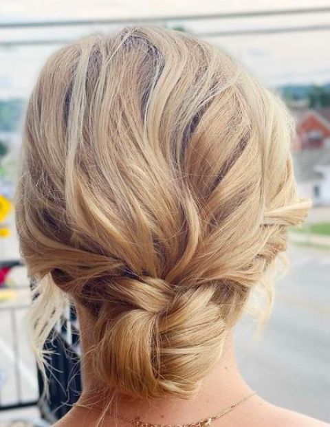 a woven low bun with a wavy bump on top and some hair down is a cool casual hairstyle for a casual wedding