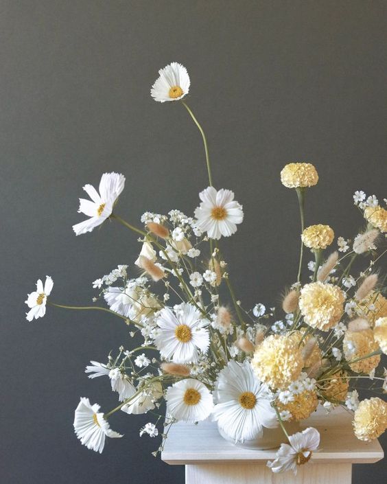 an airy wedding centerpiece of white cosmos, baby's breath and yellow carnations is cool for spring and summer