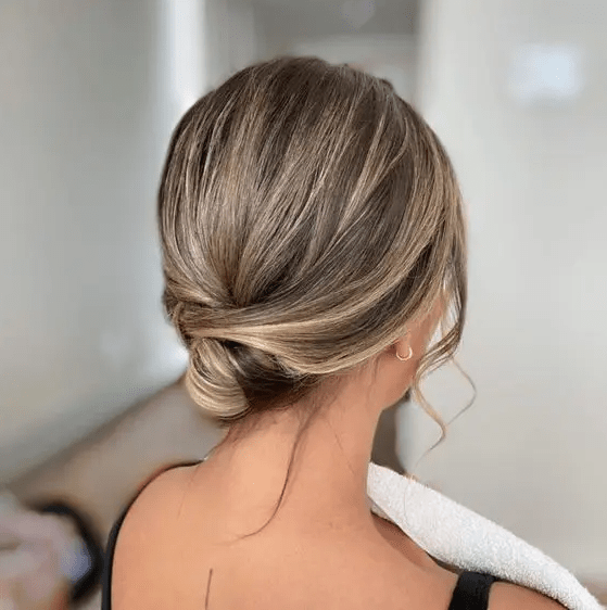 an elegant and sleek wrapped low updo with a sleek top and face-framing hair is perfect for a special occasion