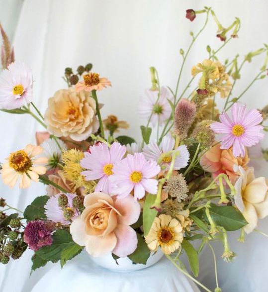 an elegant summer wedding centerpiece of pink cosmos, yellow roses and some fillers including berries