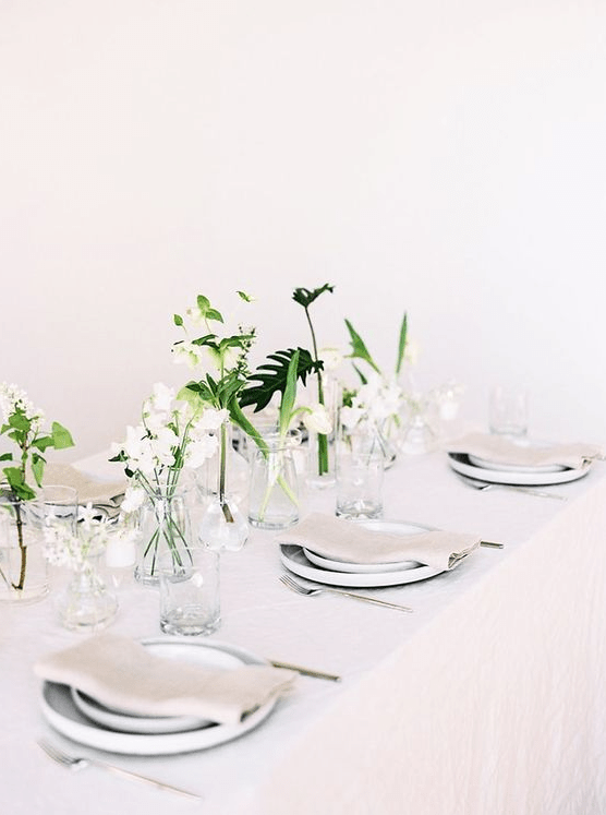 an ethereal Nordic tablescape with neutral linens, porcelain, white blooms and greenery and candles around
