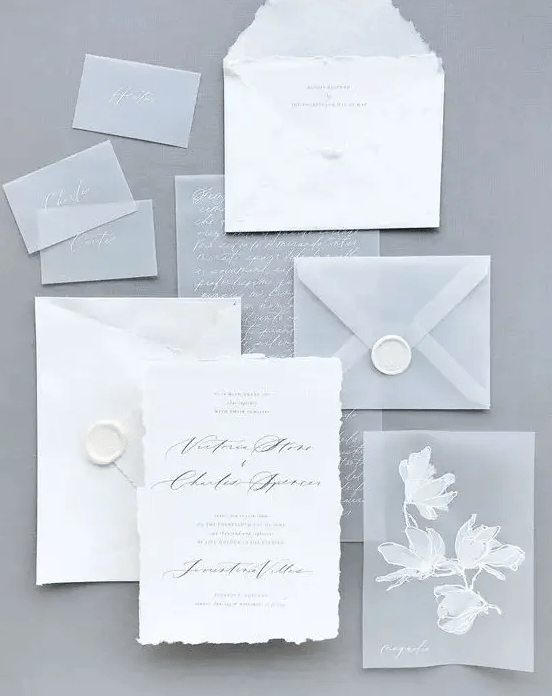 an ethereal winter wedding invitation suite with textural paper parts, a vellum envelope and vellum invites and cards with florals