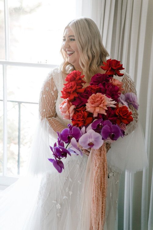 an extra bold wedding bouquet of red and peachy roses, purple and lilac cascading orchids is amazing for a bold wedding