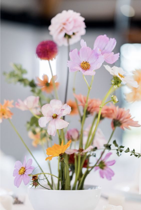 an ikebana centerpiece of pink, yellow and coral cosmos is a chic idea for a modern colorful wedding