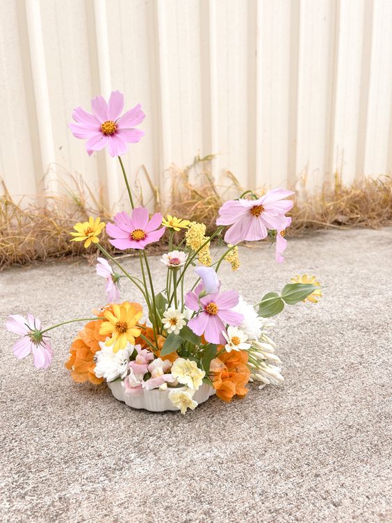 an ikebana wedding centerpiece of pink, white and yellow cosmos and orange sweet peas is a cool idea for a summer wedding