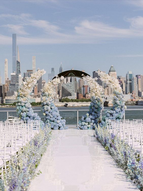 an ombre wedding altar from blue to white, with white, lilac and blue blooms lining up the aisle for a seaside wedding