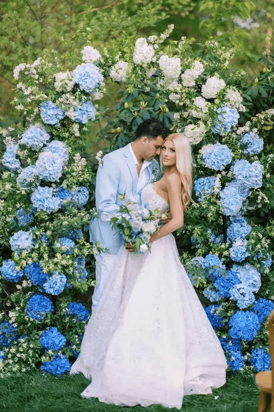 an ombre wedding arch composed of greenery and bold blue, light blue and white hydrangeas is a gorgeous idea for a blue wedding