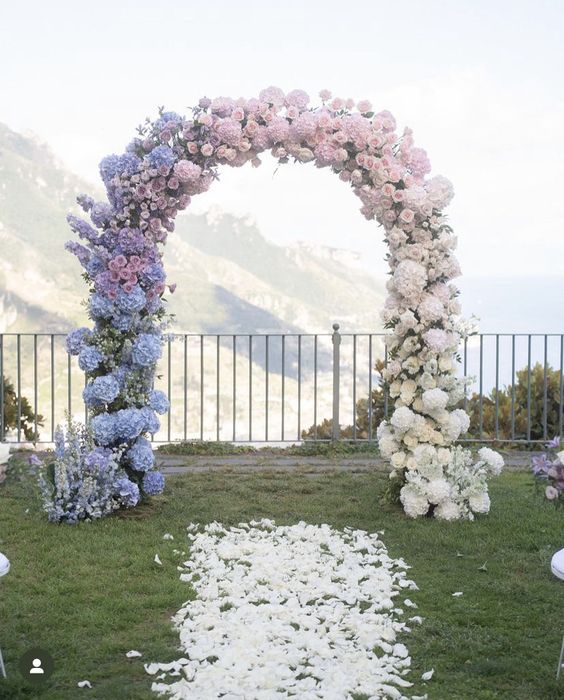 an ombre wedding arch from blue to lilac, blush and white is a beautiful and chic idea for an ombre wedding