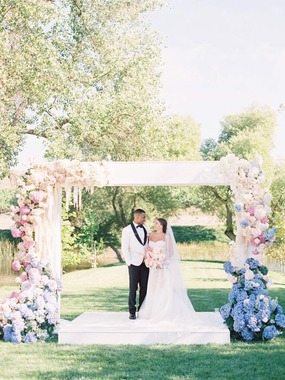 an ombre wedding arch from blue to pink and ivory is a stunning idea for a pastel-infused wedding