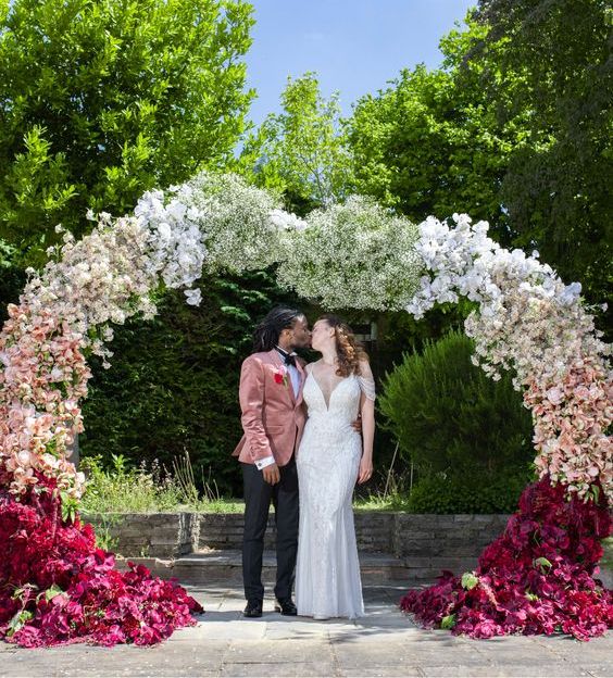 an ombre wedding arch from burgundy to pink and white is a creatively shaped piece for a whimsical wedding