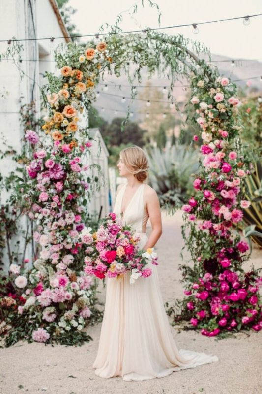 an ombre wedding arch from light pink to orange, blush and hot pink is adorable for a bright summer wedding