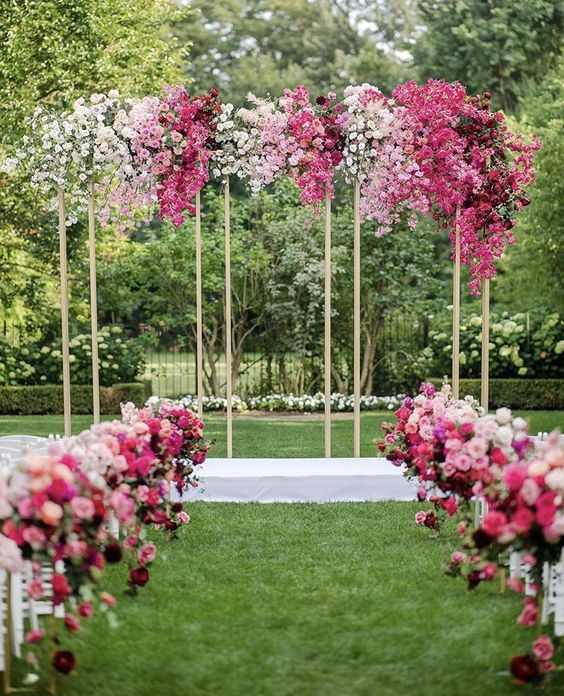 an ombre wedding arch from white to pink and burgundy plus matching florals along the aisle is adorable and chic