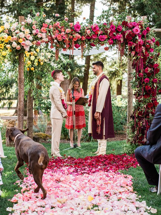 an ombre wedding arch from yellow to pink, hot pink and burgundy plus petals on the ground is a fantastic idea for a colorful wedding