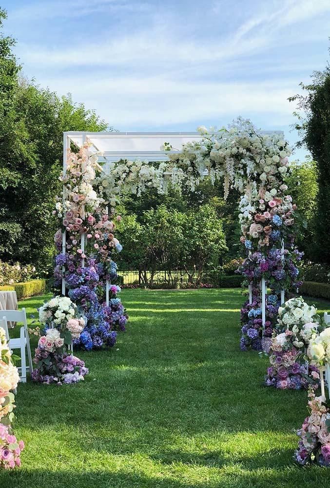 an ombre wedding arch with purple, blue, pink and white blooms and greenery is amazing for a summer wedding