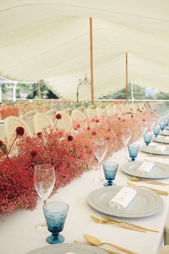 an ombre wedding centerpiece from deep red to light pink, with lots of baby’s breath for a bold wedding in summer
