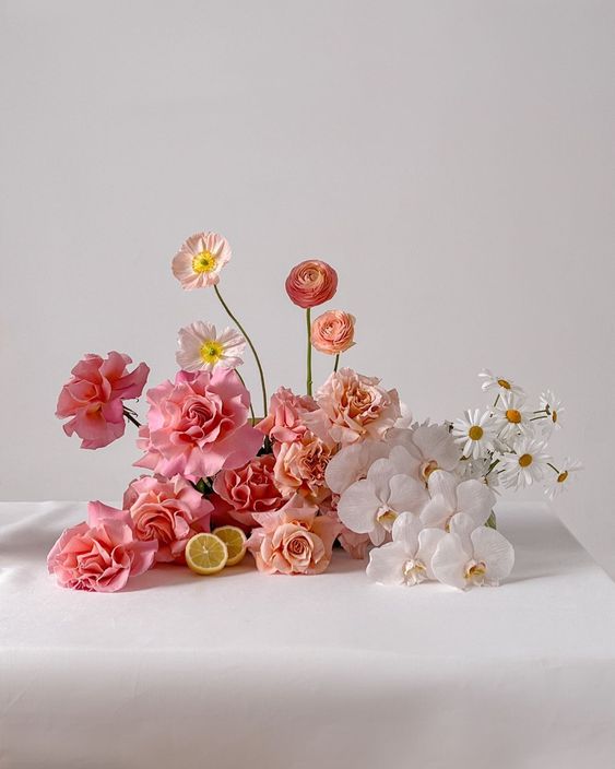 an ombre wedding centerpiece from pink to blush and white, with roses, ranunculus, orchids and chamomiles is wow
