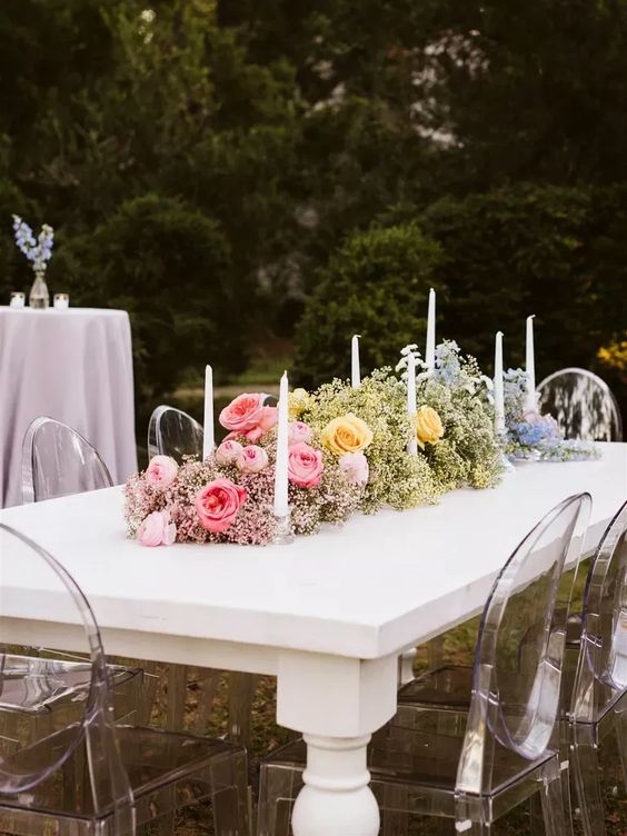 an ombre wedding centerpiece from pink to yellow and blue, with baby's breath and roses is amazing for a summer wedding