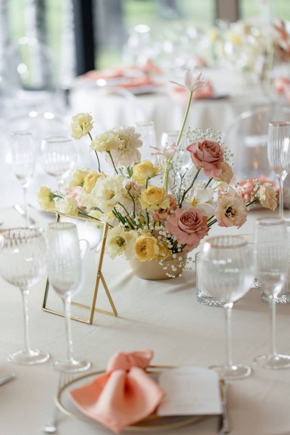 an ombre wedding centerpiece from yellow to ivory and pink blooms and baby's breath is a chic idea for spring