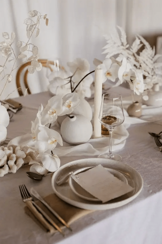 cluster white wedding centerpieces of orchids, lunaria and spray painted fern leaves are amazing