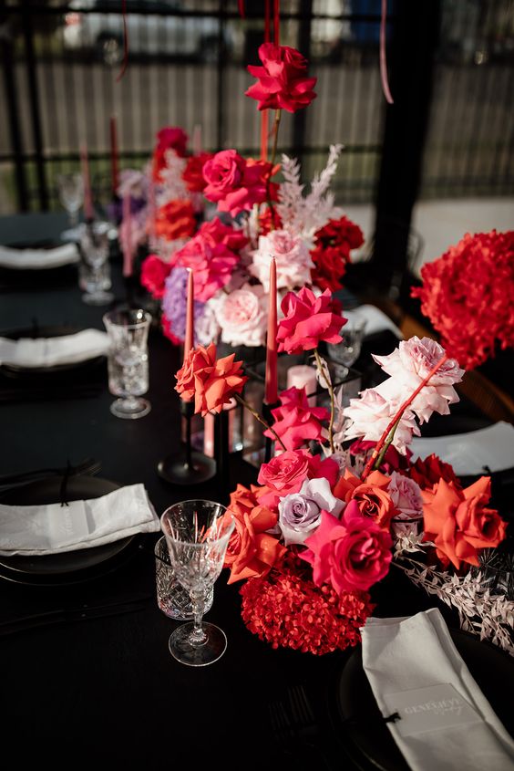 colorful rose wedding centerpieces of red, orange, blush and hot pink blooms and matching pink candles