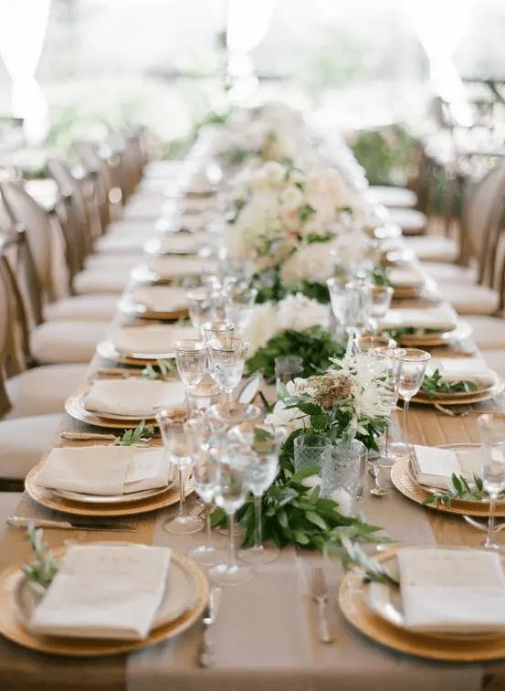 Garland running the length of the table, gold rimmed stemware, gold chargers