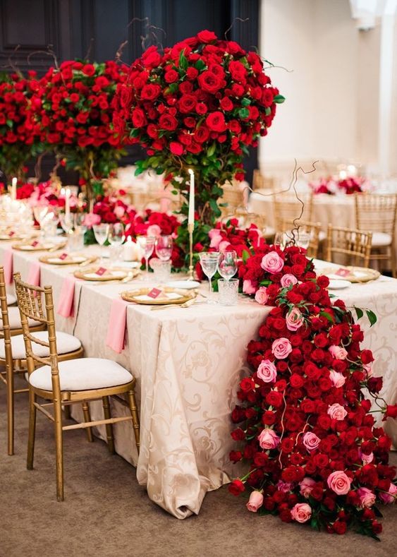 lush and bold wedding centerpiece of red, burgundy and pink roses all over the table to turn the reception into a garden