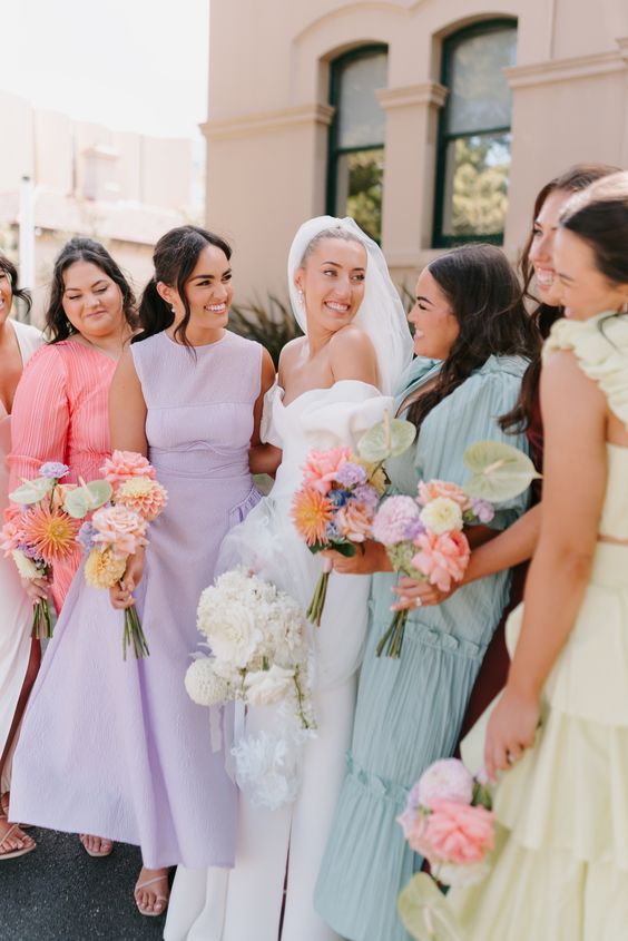 mismatched pastel midi and maxi bridesmaid dresses in pink, lilac, aqua and yellow for a pastel-colored wedding