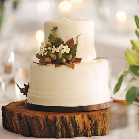 a white wedding cake decorated with bold fall leaves, blooms and a couple of acorns is a chic idea for a modern fall wedding
